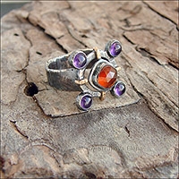 Перстень с гранатом-гессонитом красно-оранжевого цвета и фиолетовыми аметистами.