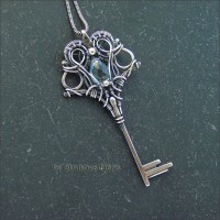 Кулон в виде стилизованного ключа с огранённым голубым топазом, выполнен из серебра, металл патинирован и частично отполирован. Размер ключа 5,5 на 2,7 см, вес 4,9 г.